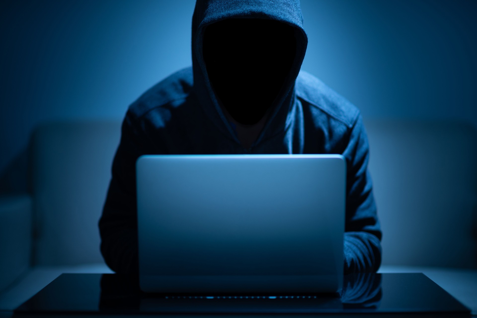 Hacker dark face using laptop